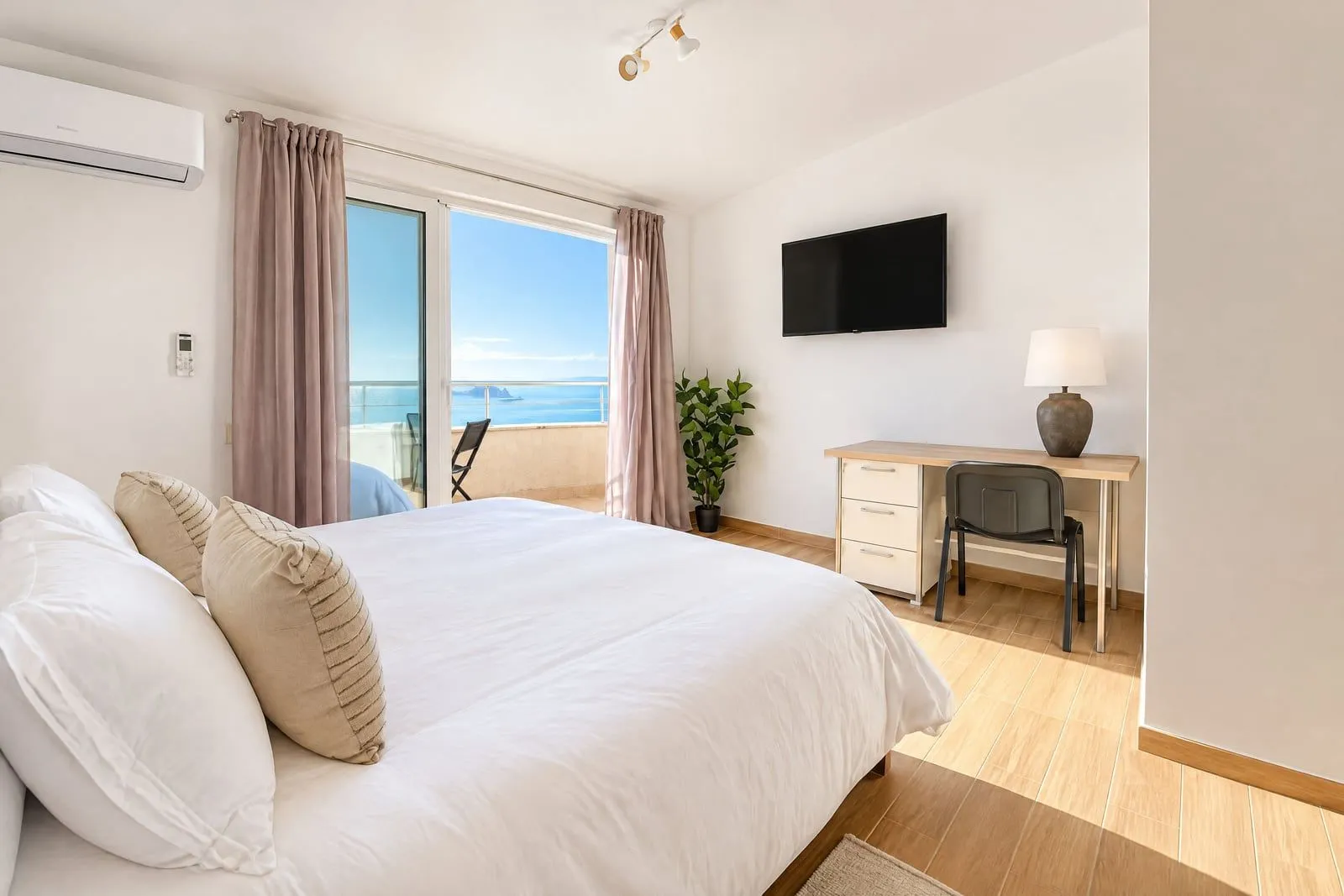 Bright bedroom with a double bed, desk, and access to a terrace with a sea view.