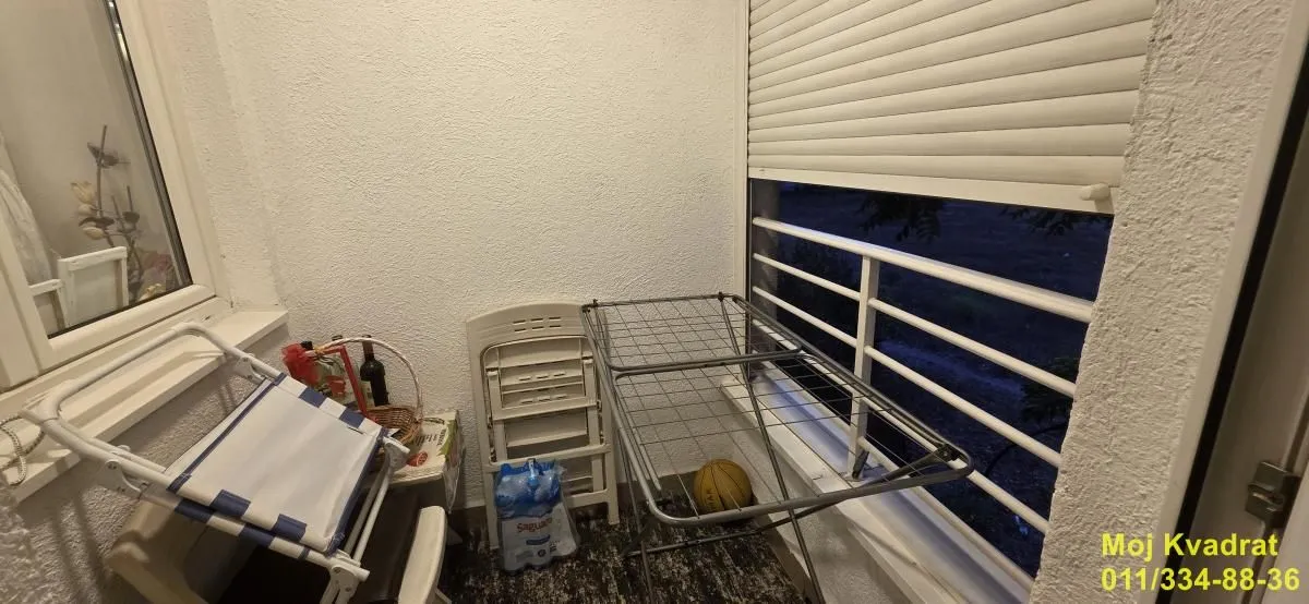 Manji natkriveni balkon sa sušilicom za veš i stolom.