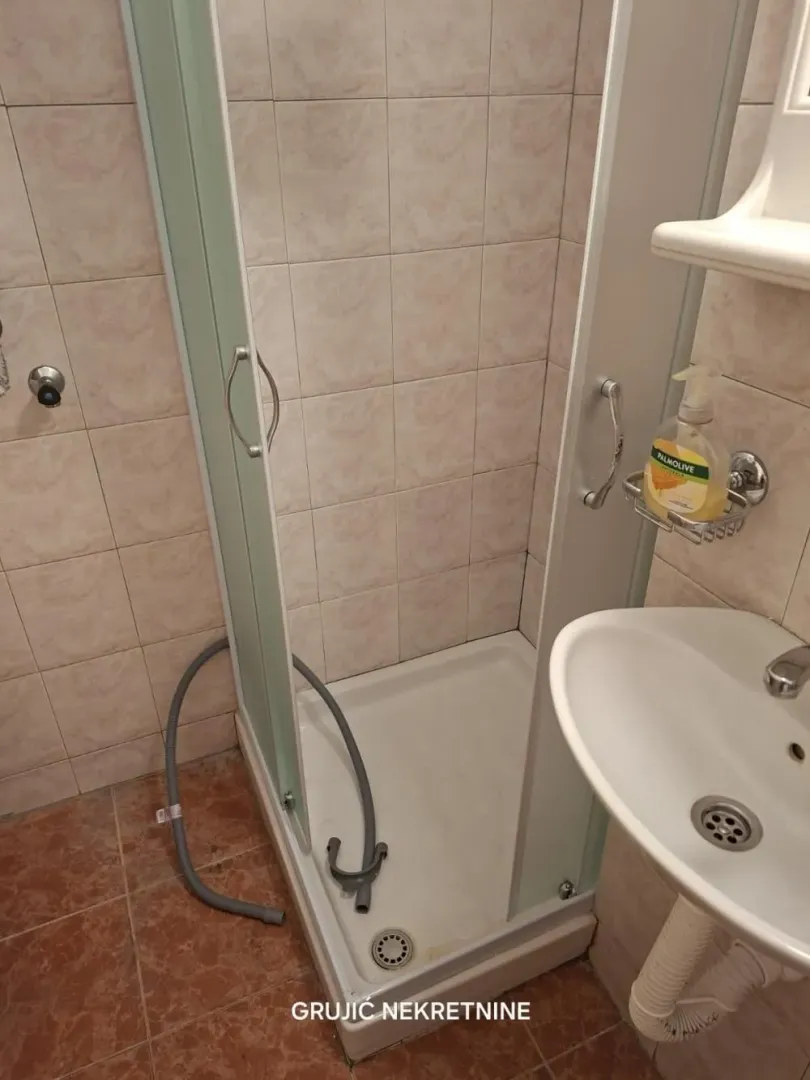 Manje kupatilo sa tuš kabinom i umivaonikom.