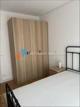 Spavaća soba sa velikim drvenim garderoberom i krevetom. - image 3