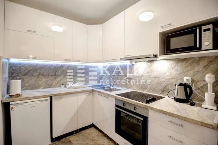 Modern white kitchen with built-in appliances and lighting.