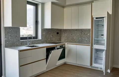Moderna kuhinja svijetlih tonova sa ugradnim aparatima i sudoperom pored prozora. - image 16