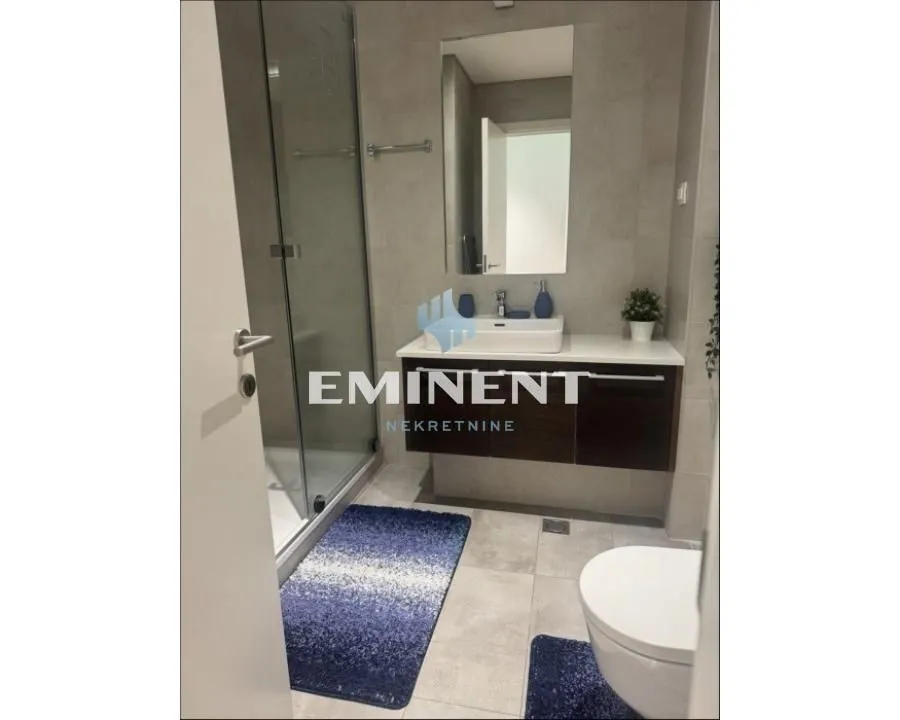 Modern bathroom with a walk-in shower, washbasin, and toilet.