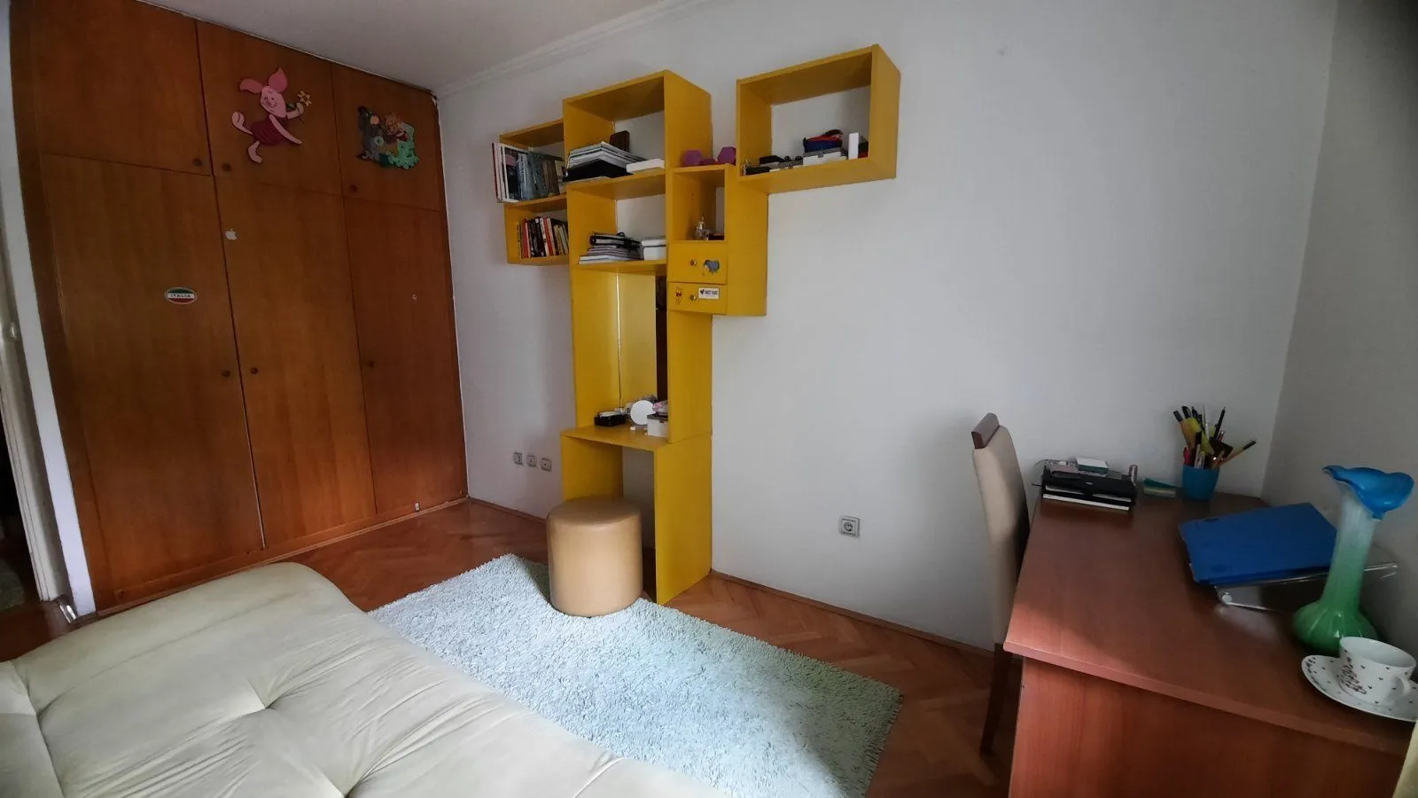 Simple bedroom with a desk and yellow shelving.
