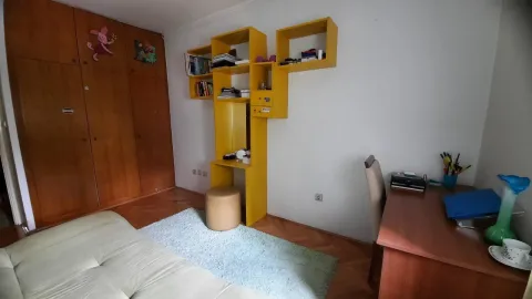 Simple bedroom with a desk and yellow shelving. - image 3