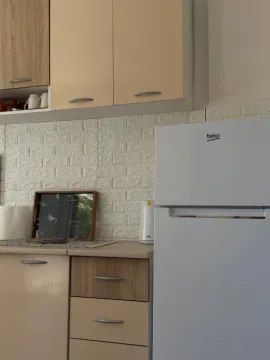 Part of the kitchen with kitchen cabinets and a refrigerator. - image 6