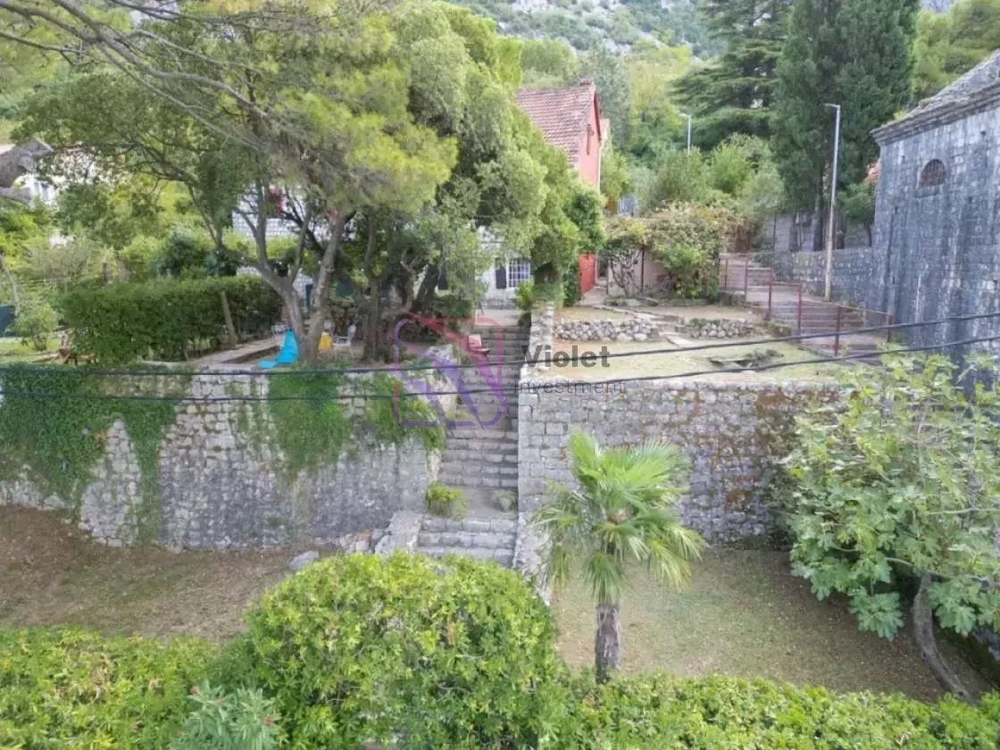 Pogled na zeleno dvorište i okolne objekte.
