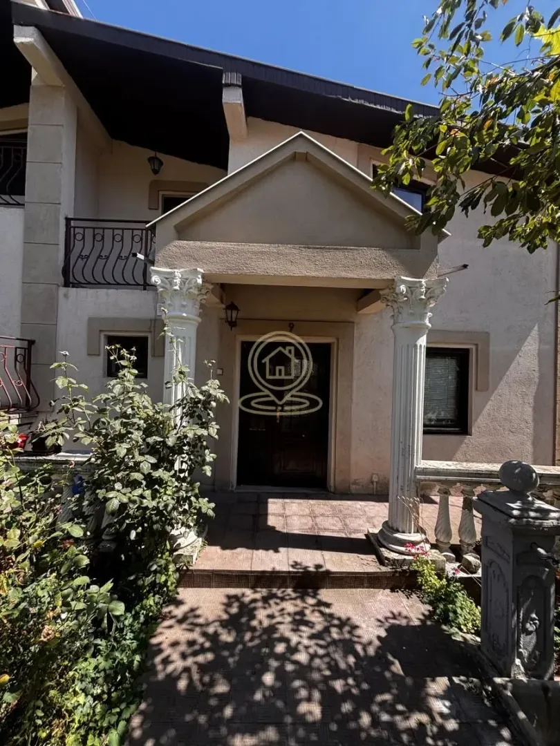 Main entrance of the house with a porch, columns, and a balcony on the upper floor.