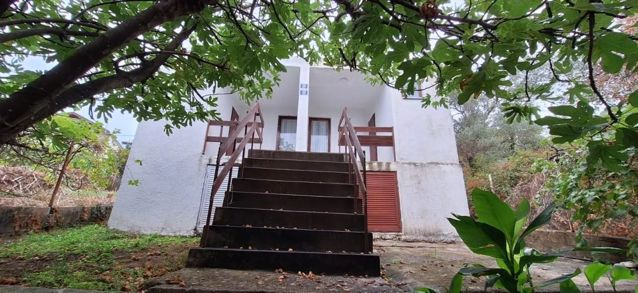 View of the exterior of the house with an external staircase and greenery in the yard.