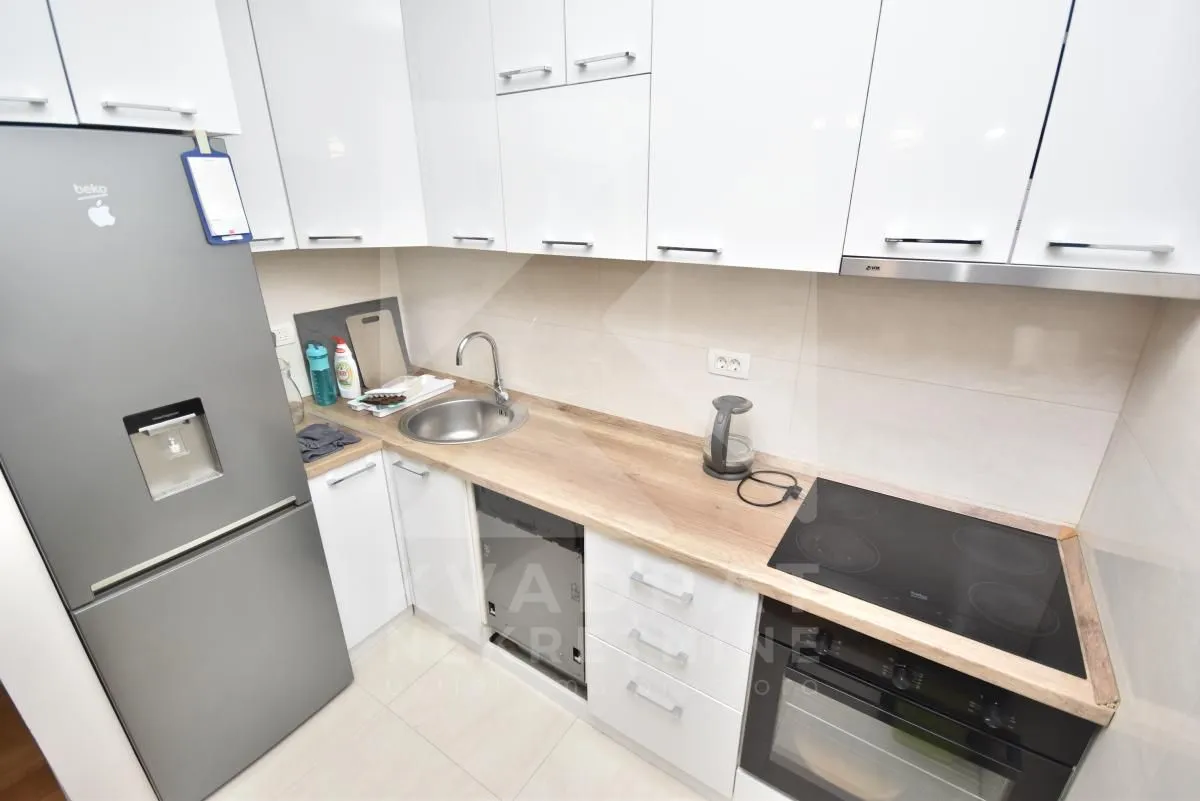 Small kitchen with white cabinets, refrigerator, and built-in appliances.