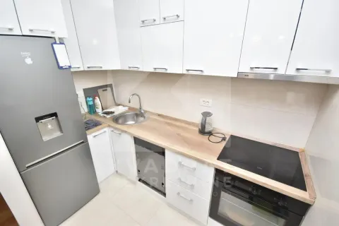 Small kitchen with white cabinets, refrigerator, and built-in appliances. - image 5