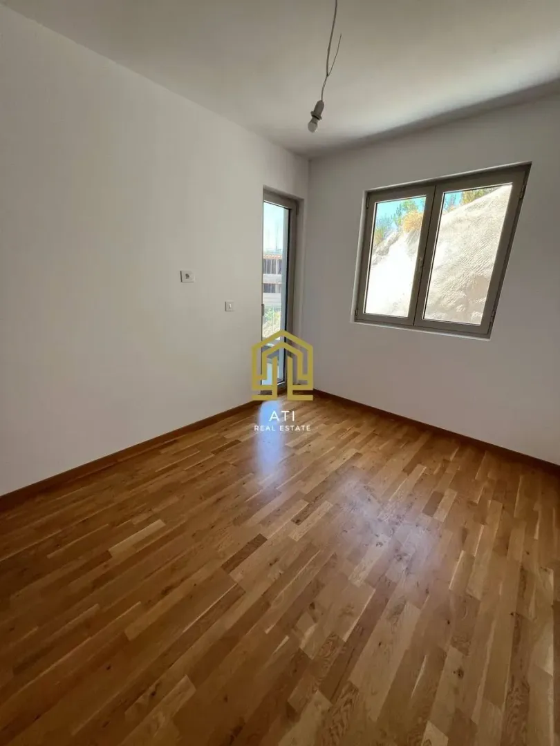 Empty room with hardwood flooring and a window.