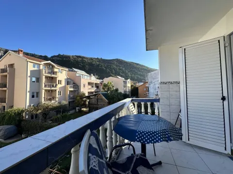 Covered balcony with seating set and view of surrounding buildings and hills. - image 2