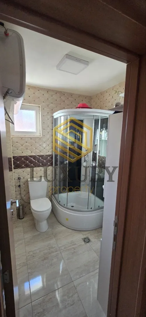 View of the bathroom with a shower cabin through an open door.