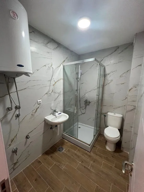 Small bathroom with a shower cabin, washbasin, and toilet.