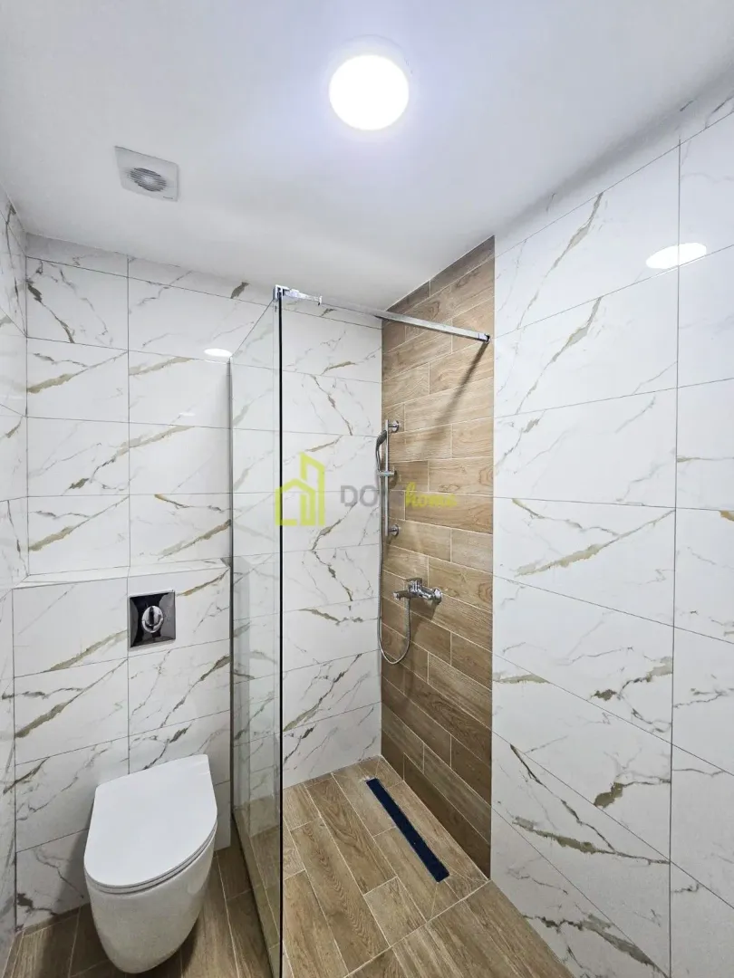 Moderne kupatilo sa tuš kabinom i ugradnom wc šoljom.