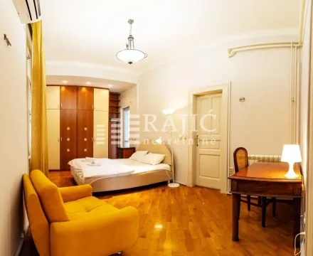 Spacious bedroom with a double bed, wardrobe, desk, and a yellow armchair. - image 15