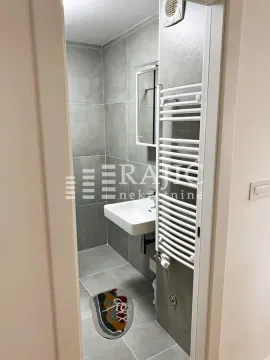 View through the doorway into a modern bathroom with grey tiles and a walk-in shower. - image 5