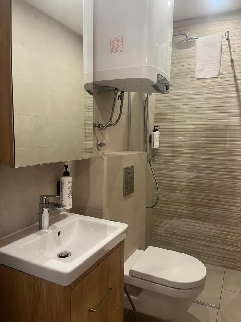 Moderno opremljeno kupatilo sa tuš kabinom, umivaonikom i WC šoljom.