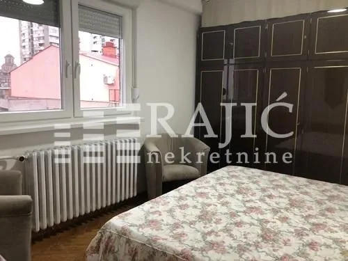 Nameštena spavaća soba sa velikim bračnim krevetom, ormarom i foteljama.