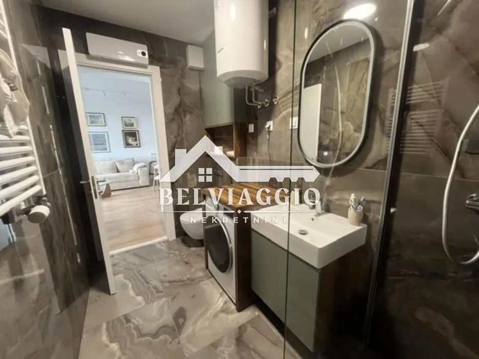 Modern bathroom equipped with a washbasin, mirror, and shower cabin.