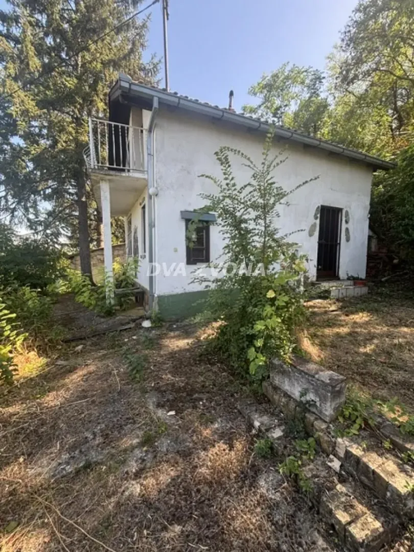Pogled na spoljašnjost kuće sa dvorištem okruženim zelenilom.