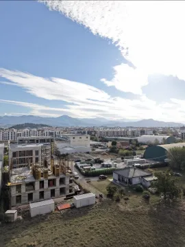 Pogled iz vazduha na gradilište i okolne objekte sa planinama u pozadini. - image 2