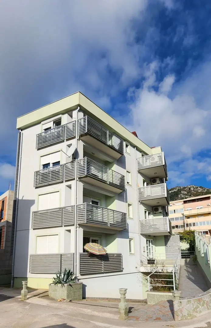 Exterior of a residential building with balconies and a landscaped yard.