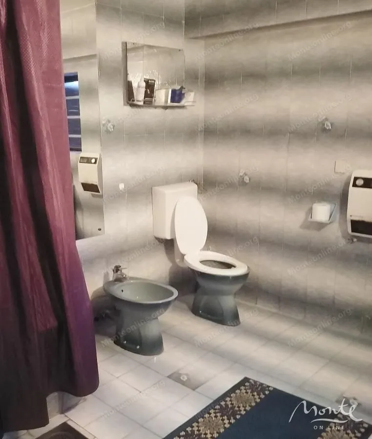 Bathroom with toilet, bidet, and ceramic tiles on the walls and floor.