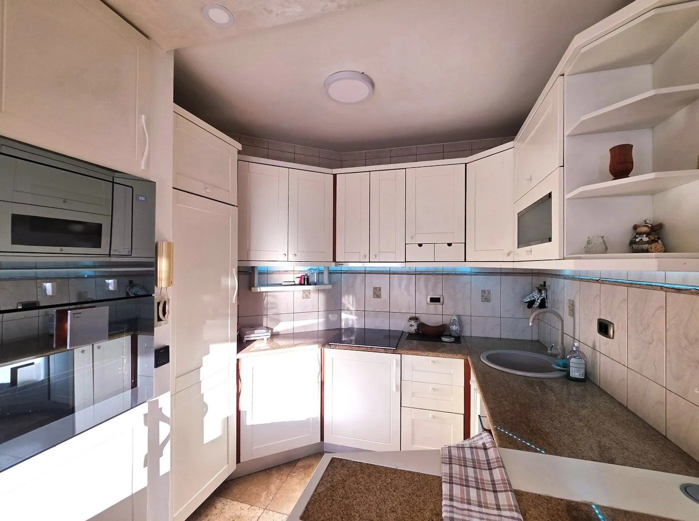 A fitted kitchen with white cabinetry and built-in appliances.