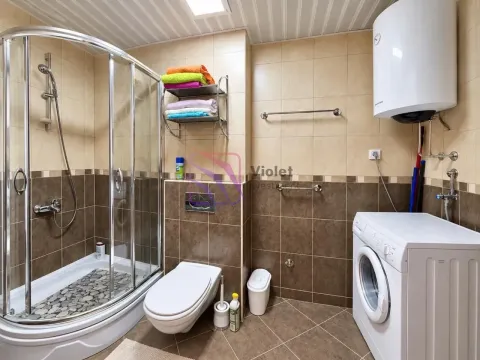 Bathroom equipped with a shower cabin, toilet, and washing machine. - image 10