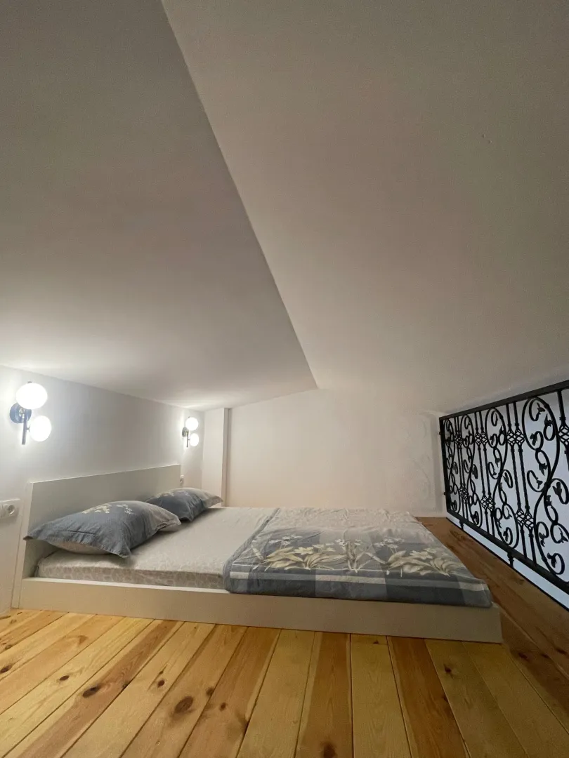 Bed in an attic room with a wooden floor.