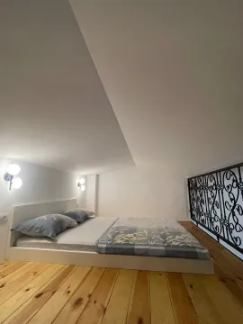 Bed in an attic room with a wooden floor. - image 10