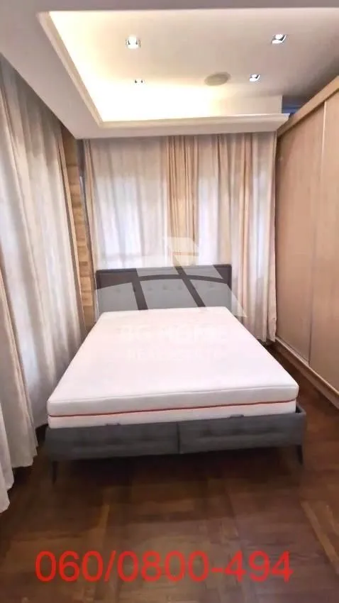 Spavaća soba sa bračnim krevetom, plakarom i prozorima sa zavesama.