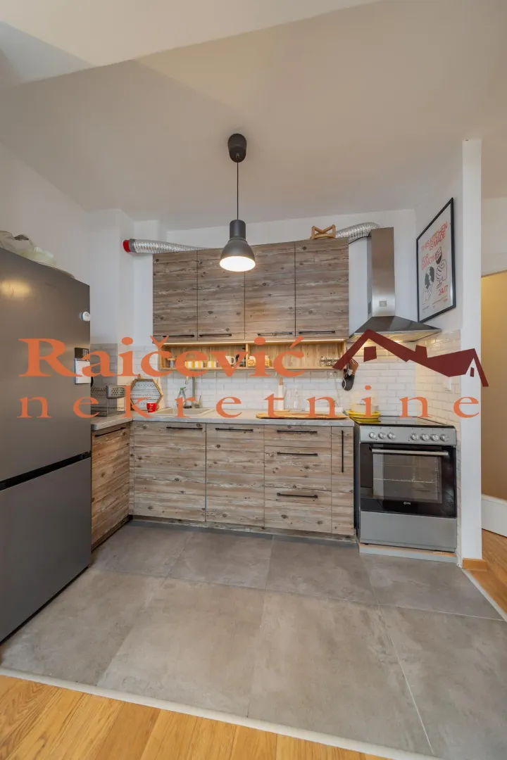 Small kitchen with wooden cabinetry and grey floor tiles.