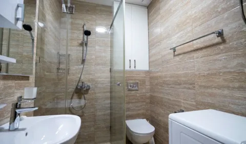Kupatilo obloženo keramičkim pločicama sa tuš kabinom, umivaonikom i wc šoljom. - image 20