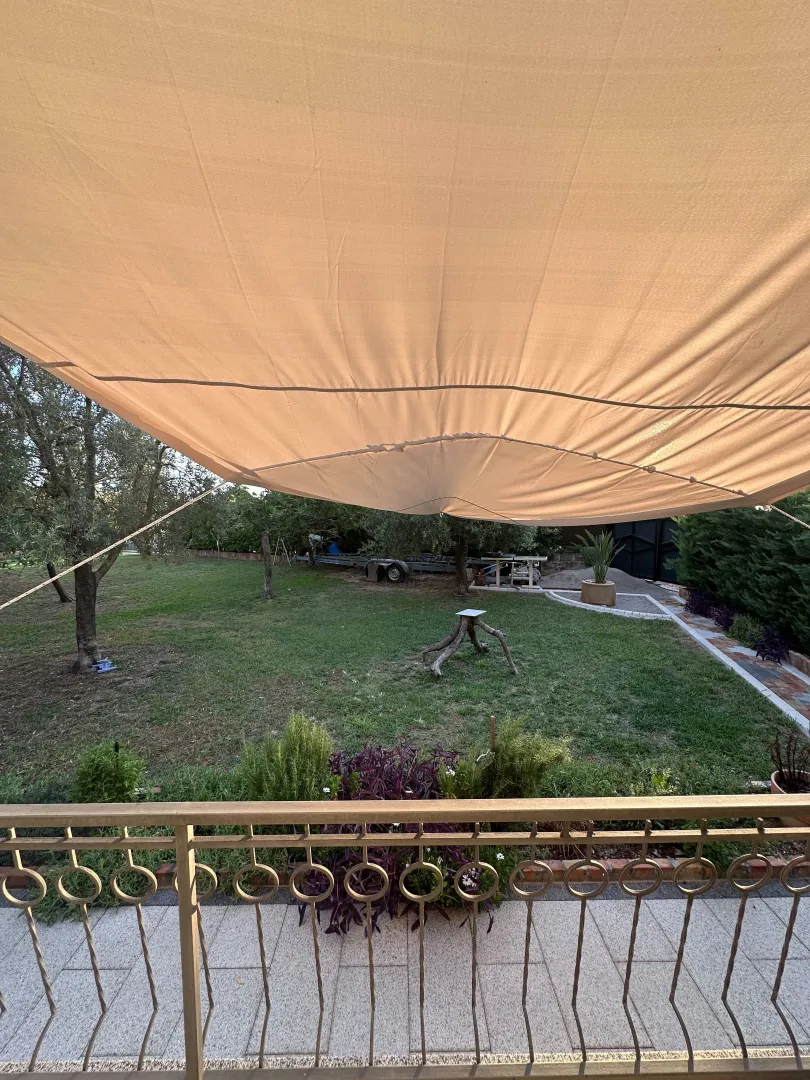Pogled iz dvorišta sa nadstrešnicom i zelenom travnatom površinom.