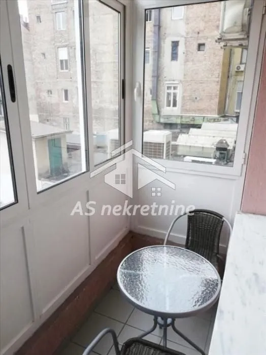 Enclosed balcony with a small table and chairs.
