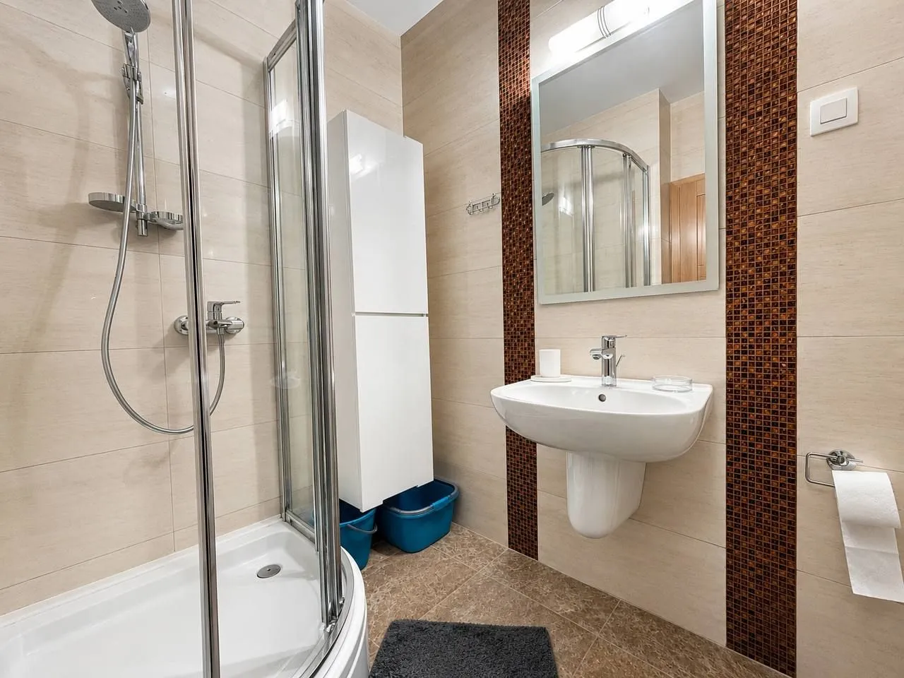 Modernly equipped bathroom with a shower cabin and sink.