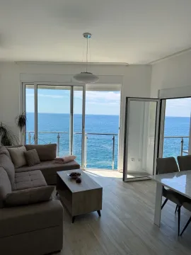 Living room with a sofa, dining table, and a sea view through glass balcony doors. - image 3
