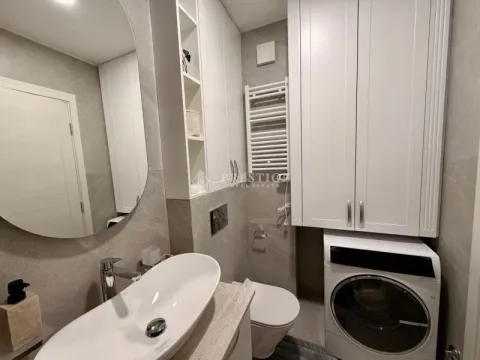 Modernly equipped bathroom with a washbasin, toilet, and washing machine. - image 17