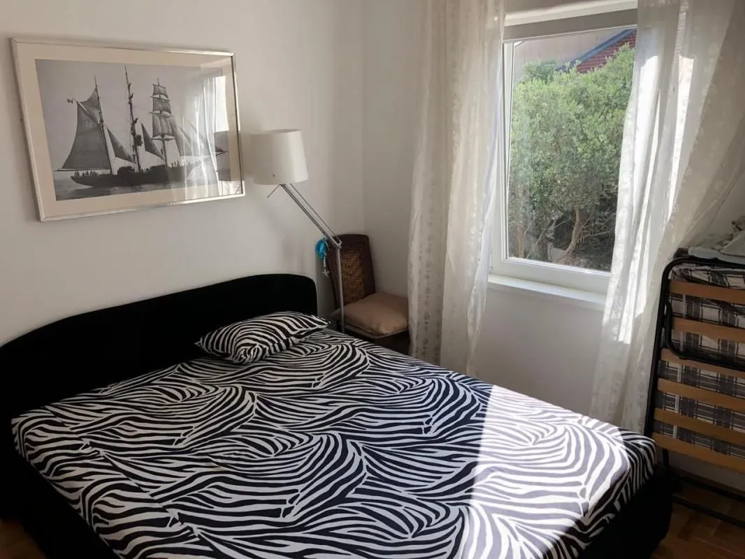 A bedroom with a double bed and a window overlooking greenery.