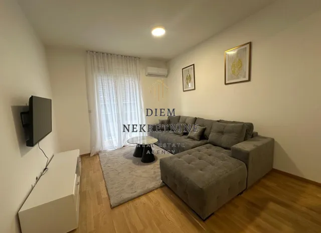 Living room with a sectional sofa, TV, and balcony access.