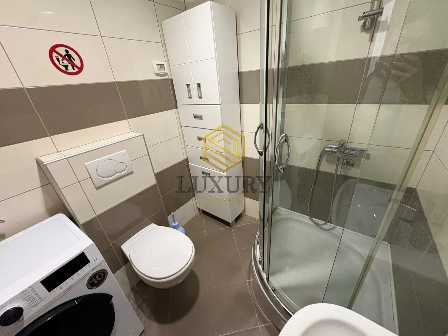 Small bathroom with a shower cabin, toilet, and white cabinetry.
