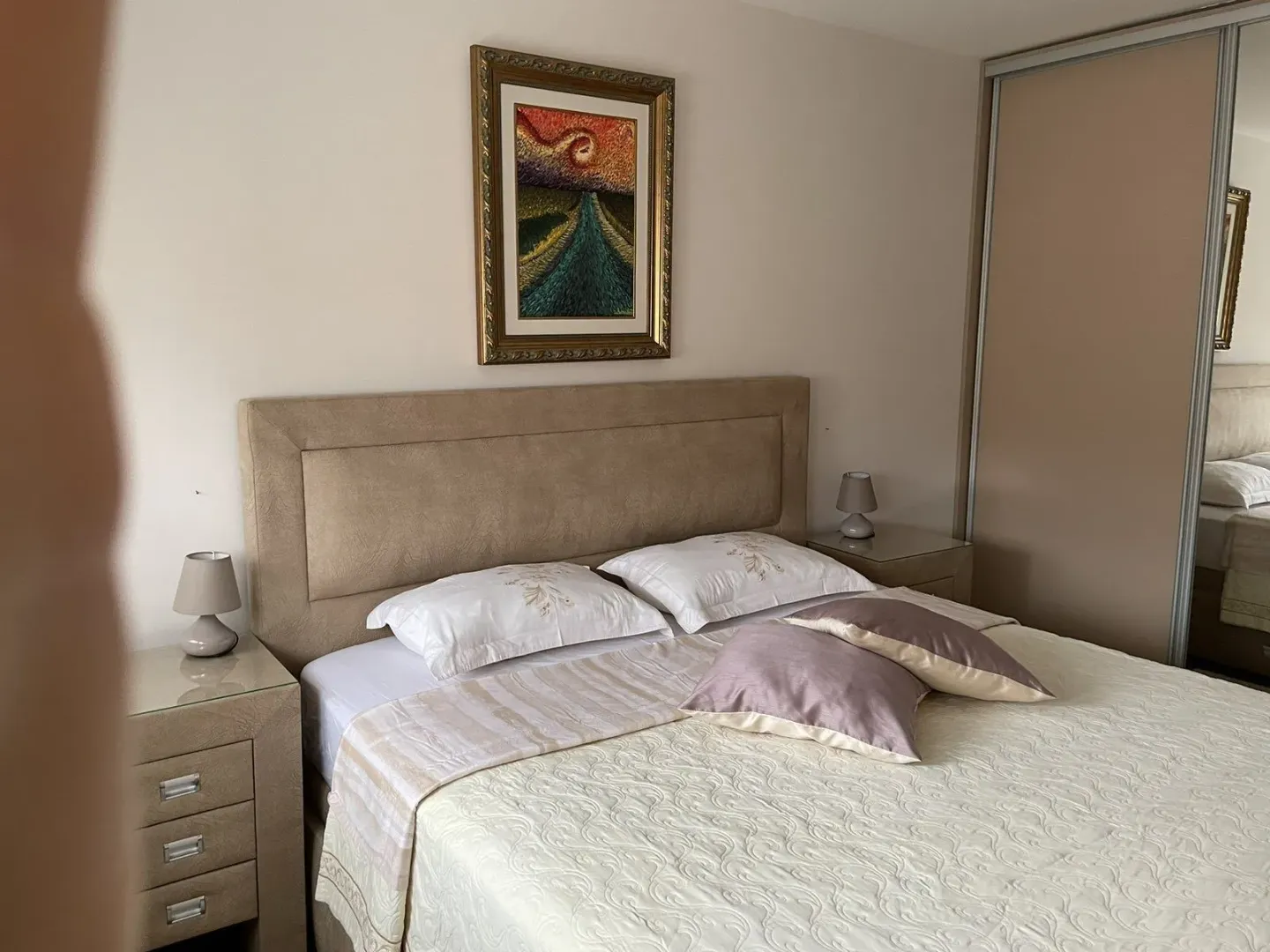 Bright bedroom with a large double bed and nightstands.