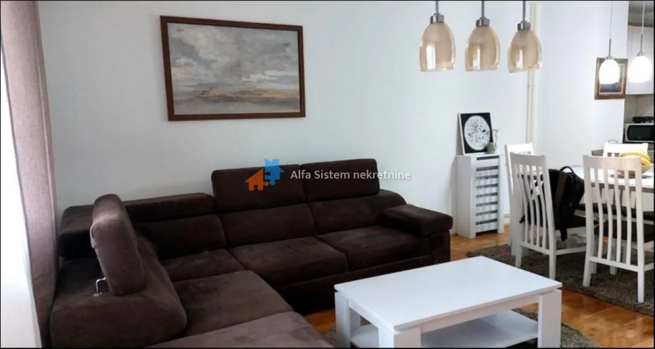 Living room with a sofa set and a dining area in the background.