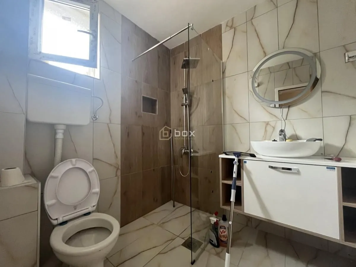 Modern bathroom with a walk-in shower, washbasin, and toilet.
