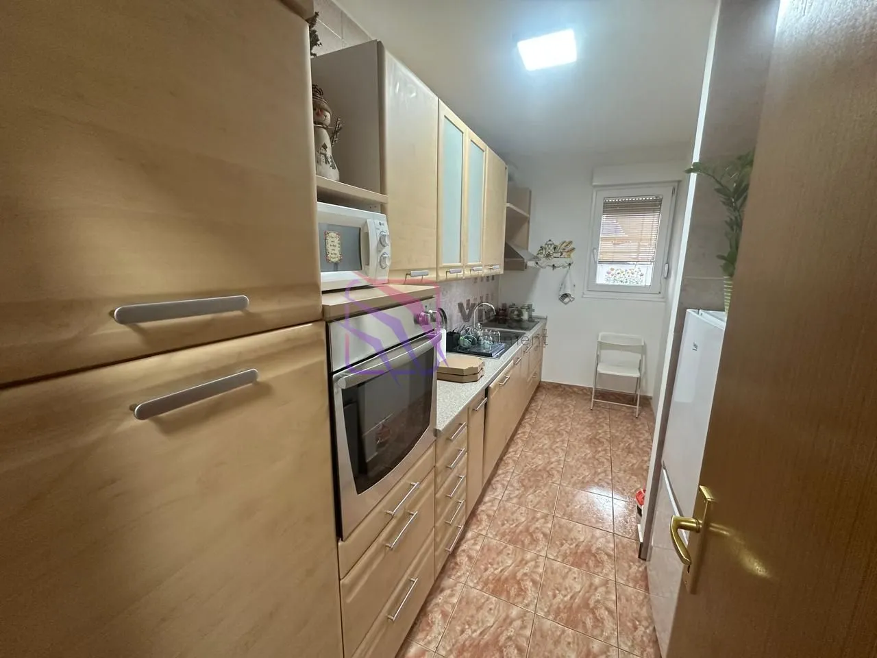 Long kitchen with wooden cabinets and a built-in oven.