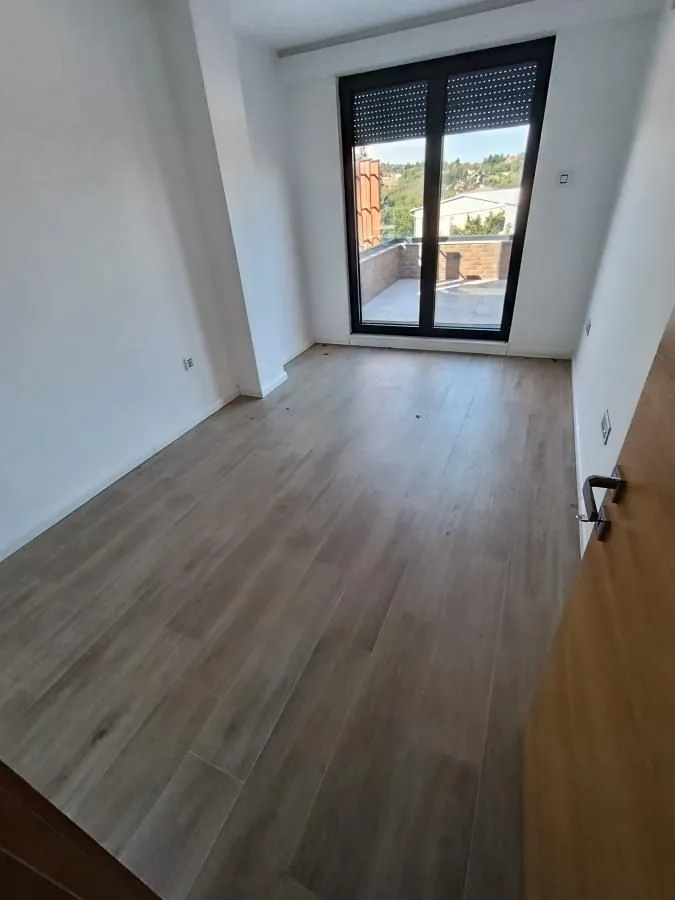 Empty room with laminate flooring and access to the terrace.