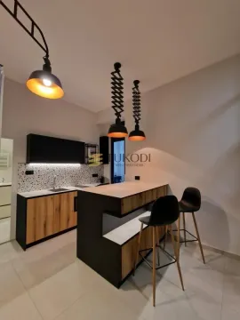 Modern kitchen with a bar counter and black pendant lights. - image 4